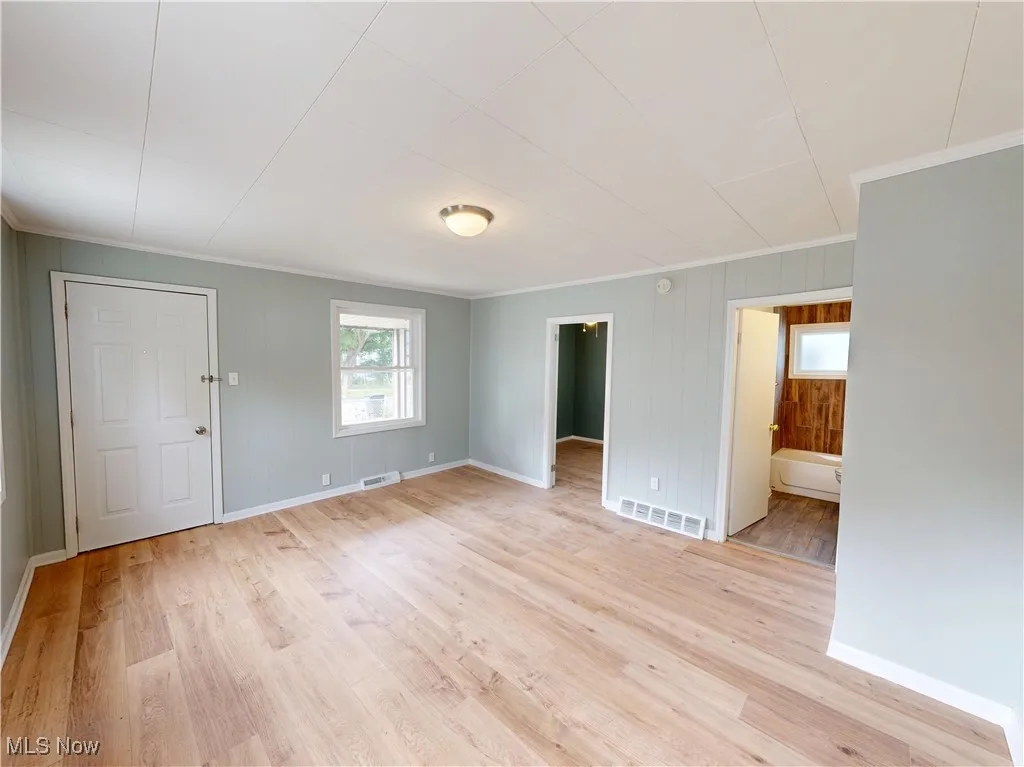Unfurnished room with crown molding, light wood finished floors, and baseboards