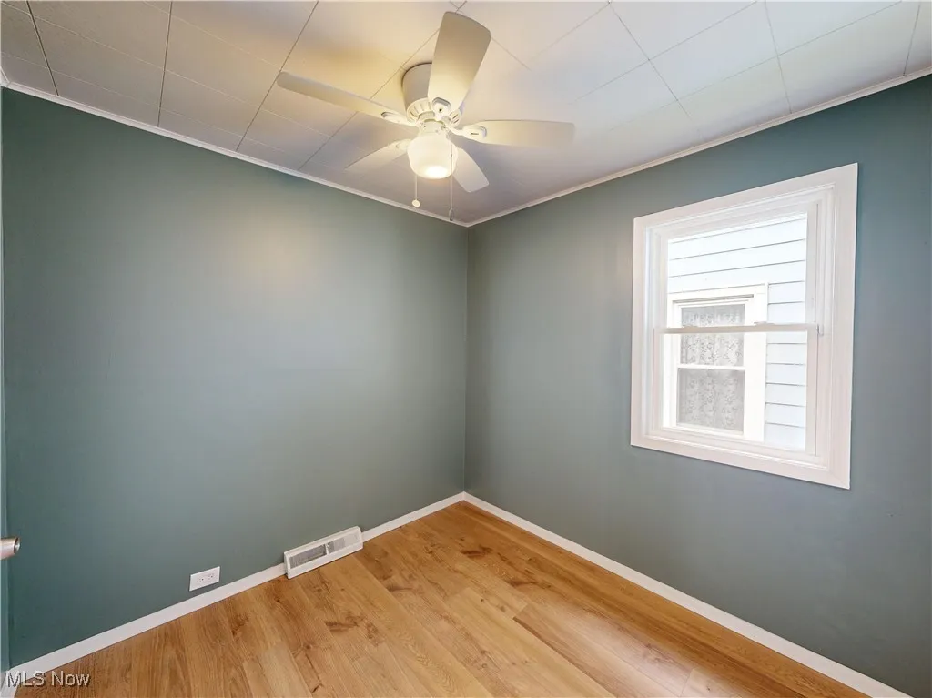 Unfurnished room with ornamental molding, wood finished floors, baseboards, and ceiling fan