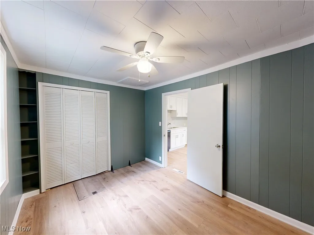 Unfurnished bedroom with light wood finished floors, a closet, ornamental molding, baseboards, and ceiling fan