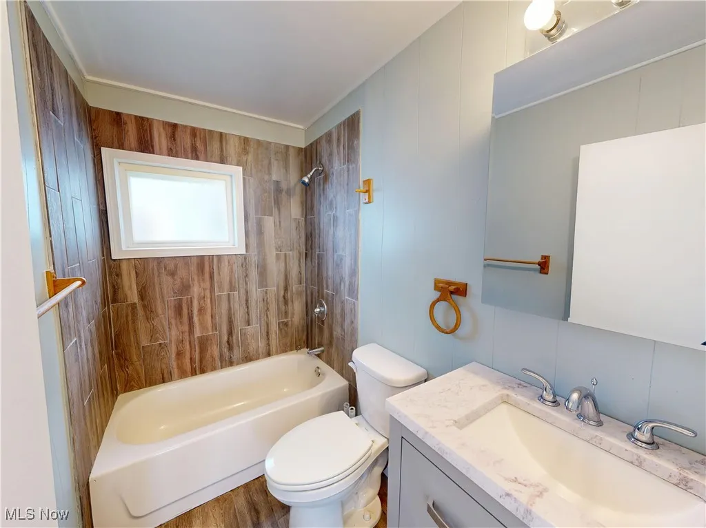 Bathroom featuring tub / shower combination, vanity, and toilet