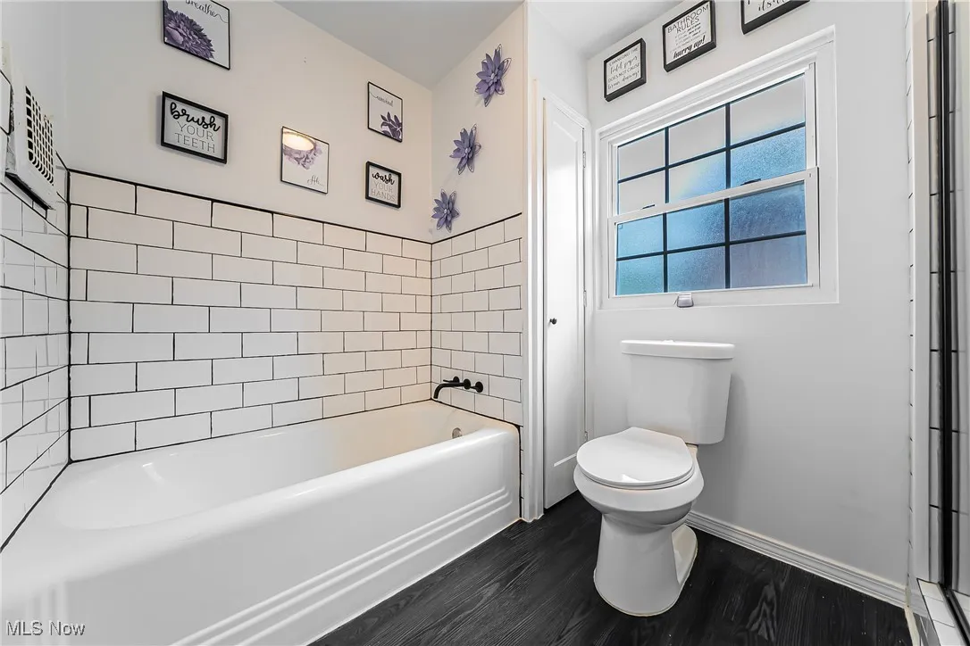Bathroom with a tub to relax in and wood finished floors
