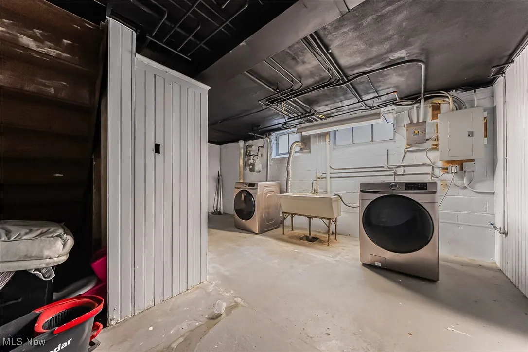 Below grade area featuring electric panel and washing machine and clothes dryer
