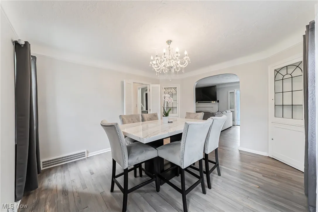 Dining area featuring arched walkways, a chandelier, and wood finished floors