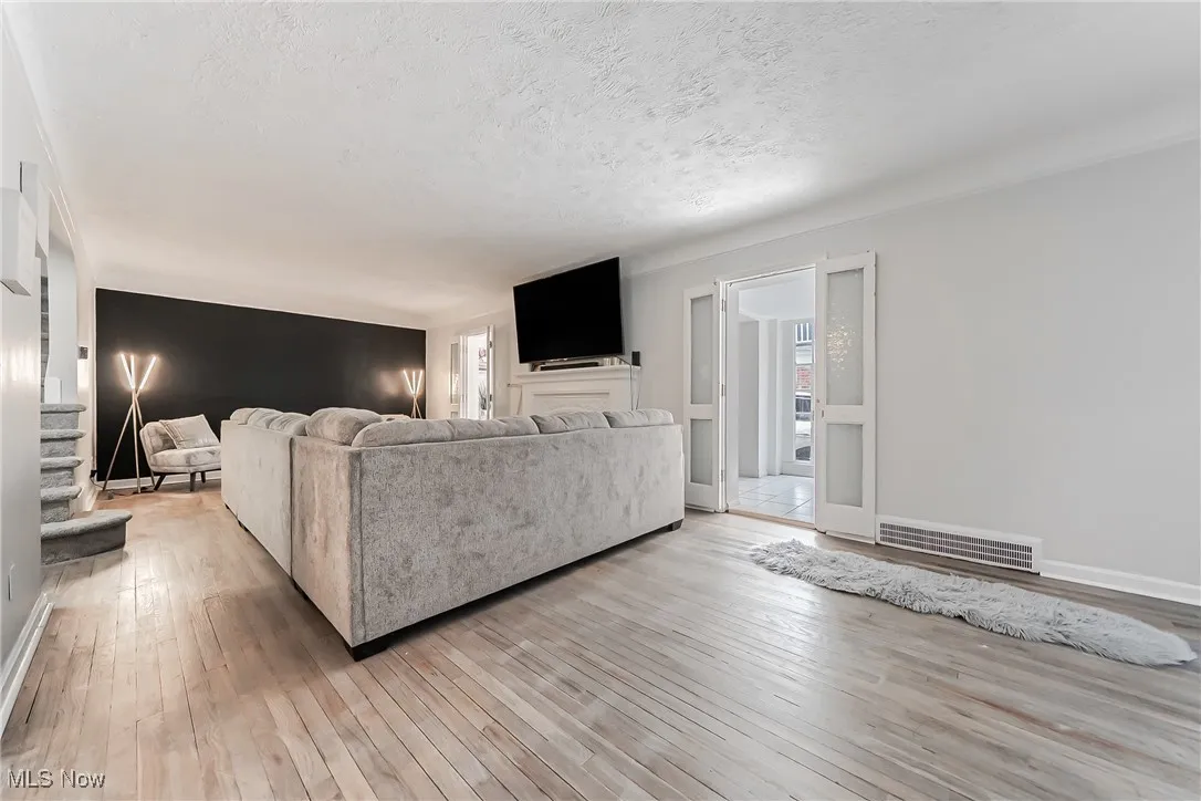 Living area featuring light wood-style flooring, a textured ceiling, and stairway