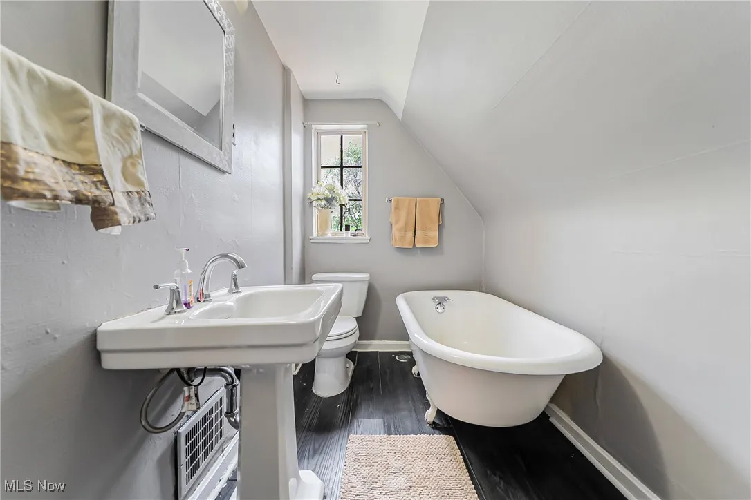 Full bath featuring lofted ceiling, a freestanding bath, and wood finished floors