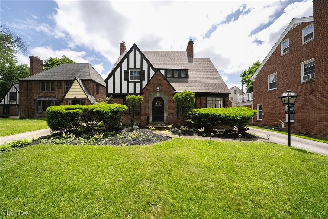 Tudor home featuring a chimney, a front yard, and brick siding