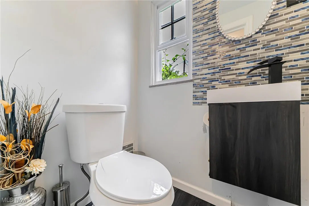 Half bathroom featuring decorative backsplash, wood finished floors, and vanity