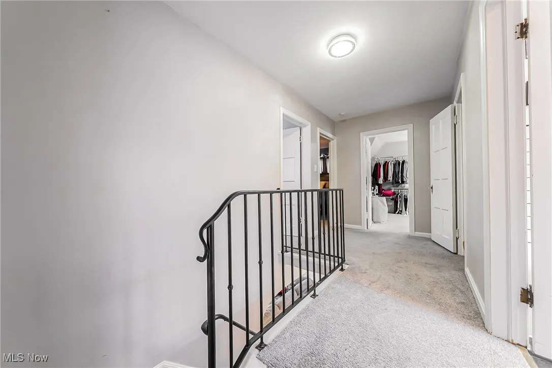 Hallway with an upstairs landing and light colored carpet