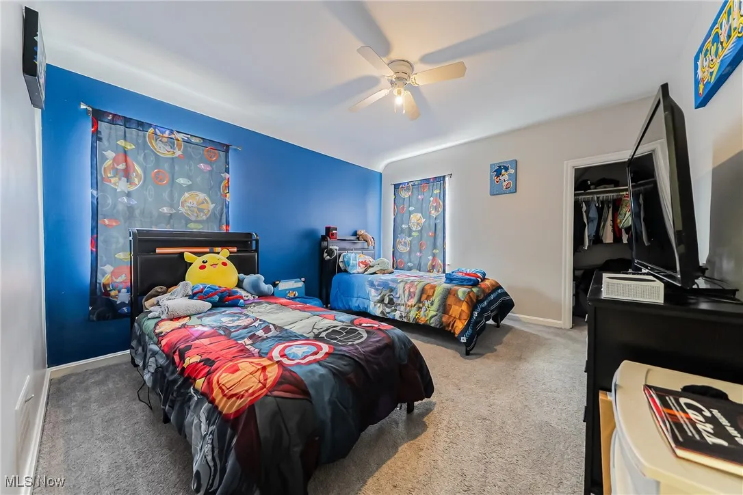 Carpeted bedroom featuring a ceiling fan and a closet