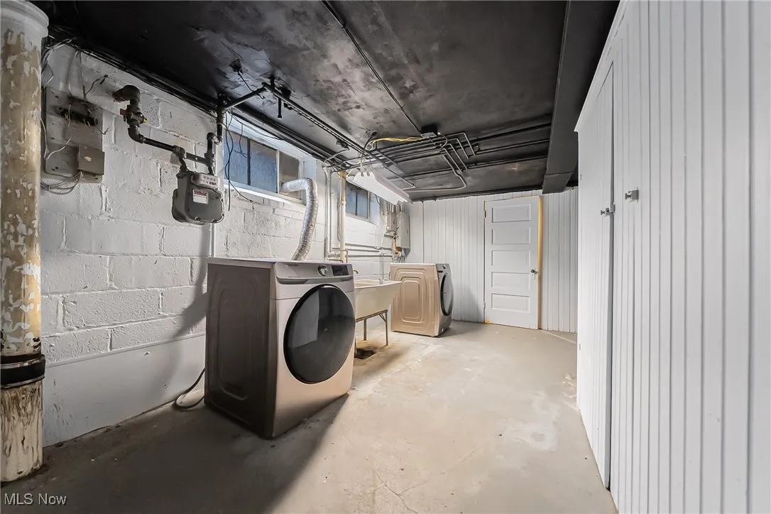 Unfinished below grade area with washer and dryer and concrete block wall