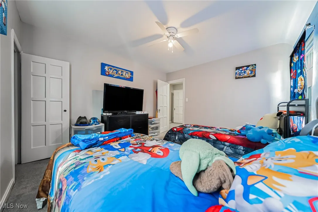 Carpeted bedroom featuring ceiling fan and vaulted ceiling
