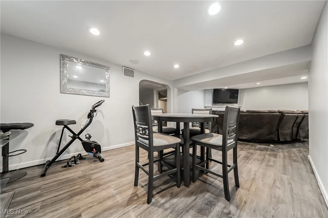 Dining area featuring wood finished floors, arched walkways, and recessed lighting