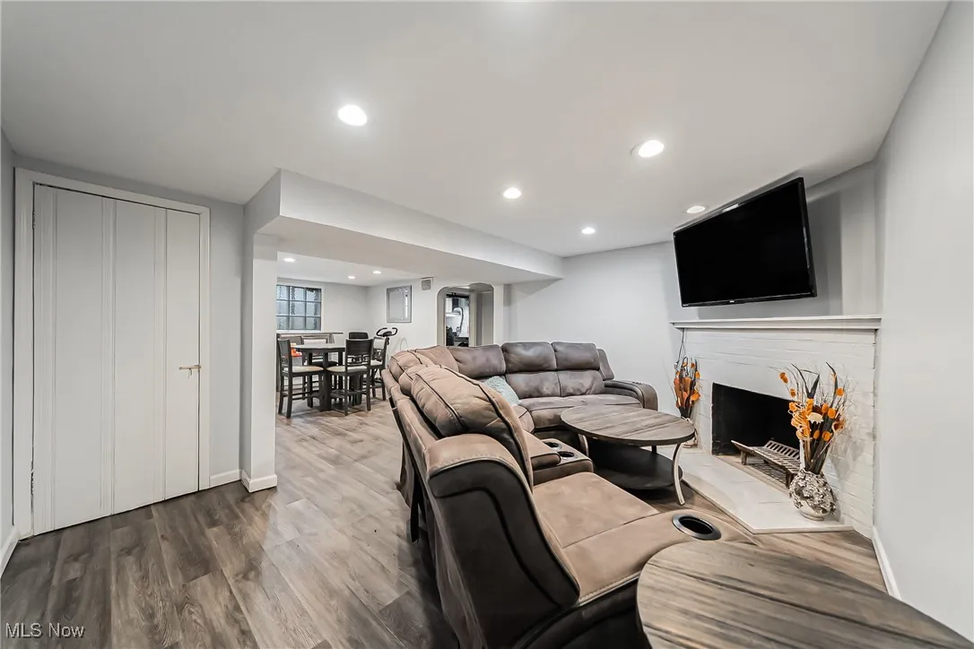 Living room with dark wood-style flooring, a fireplace, and recessed lighting