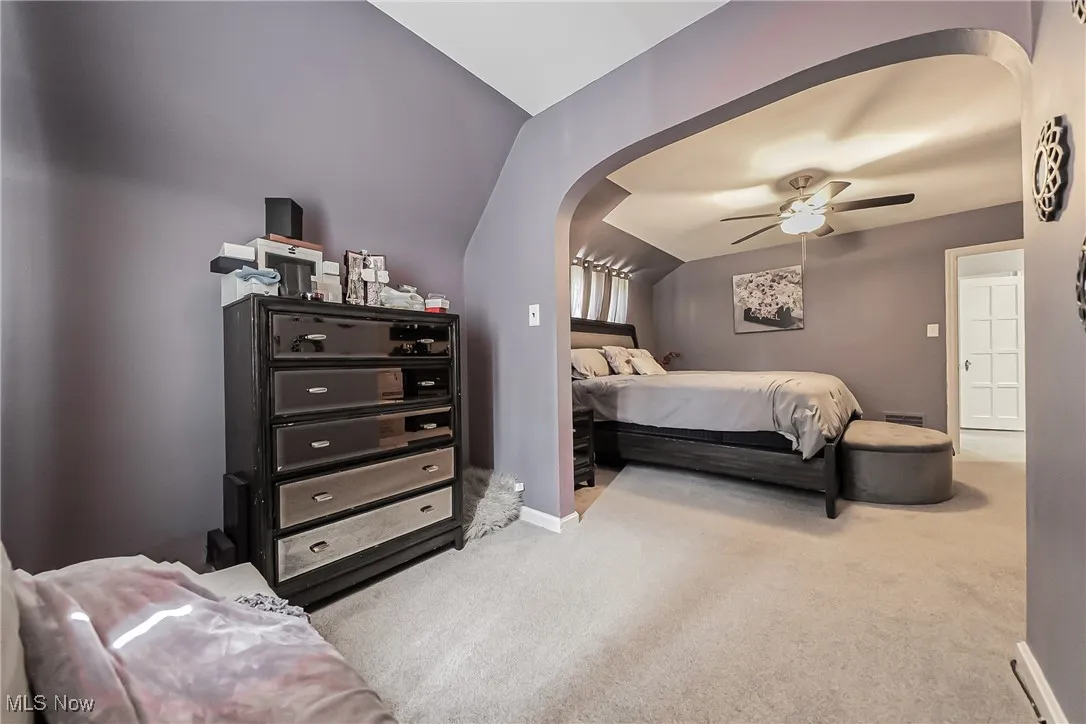 Bedroom featuring arched walkways, carpet, lofted ceiling, and a ceiling fan
