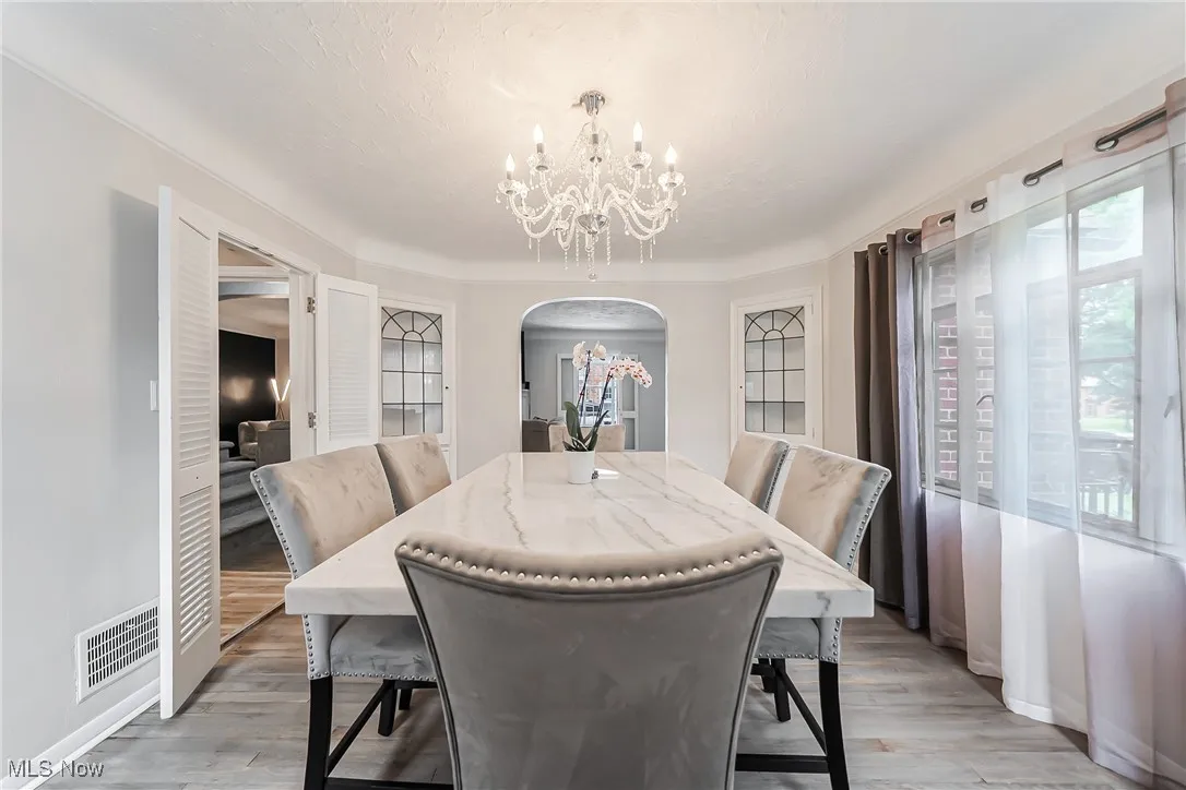 Dining area with arched walkways, a chandelier, and light wood-style floors