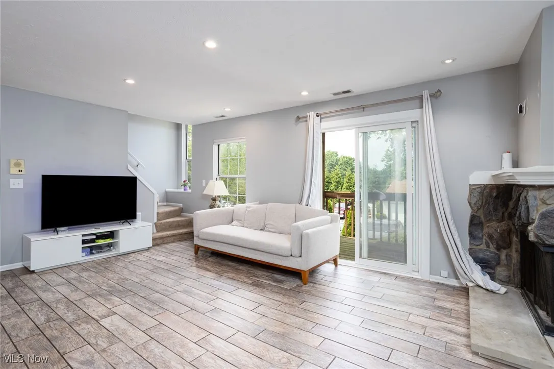 Living area with stairs, a fireplace, healthy amount of natural light, recessed lighting, and wood finished floors