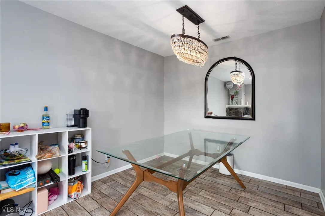 Dining room with a chandelier, wood tiled floors, and baseboards