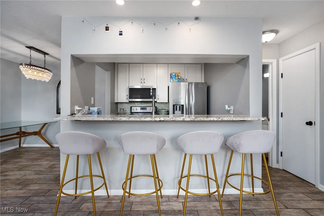 Kitchen with stainless steel appliances, a breakfast bar, decorative backsplash, a peninsula, and recessed lighting