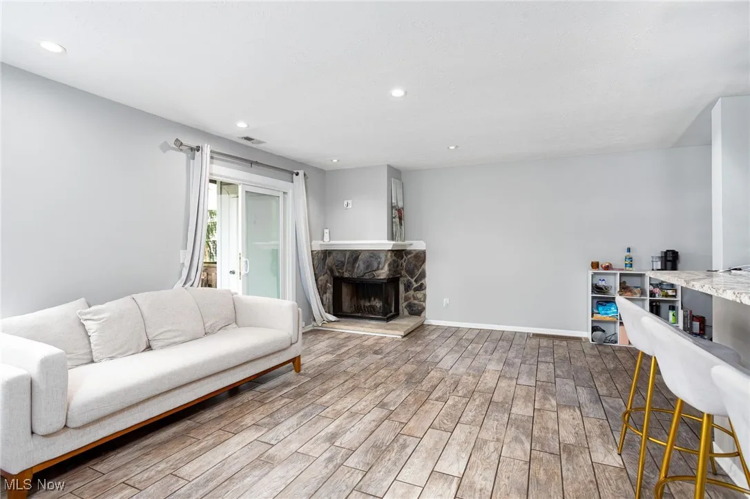 Living area featuring wood finished floors, recessed lighting, a stone fireplace, and baseboards