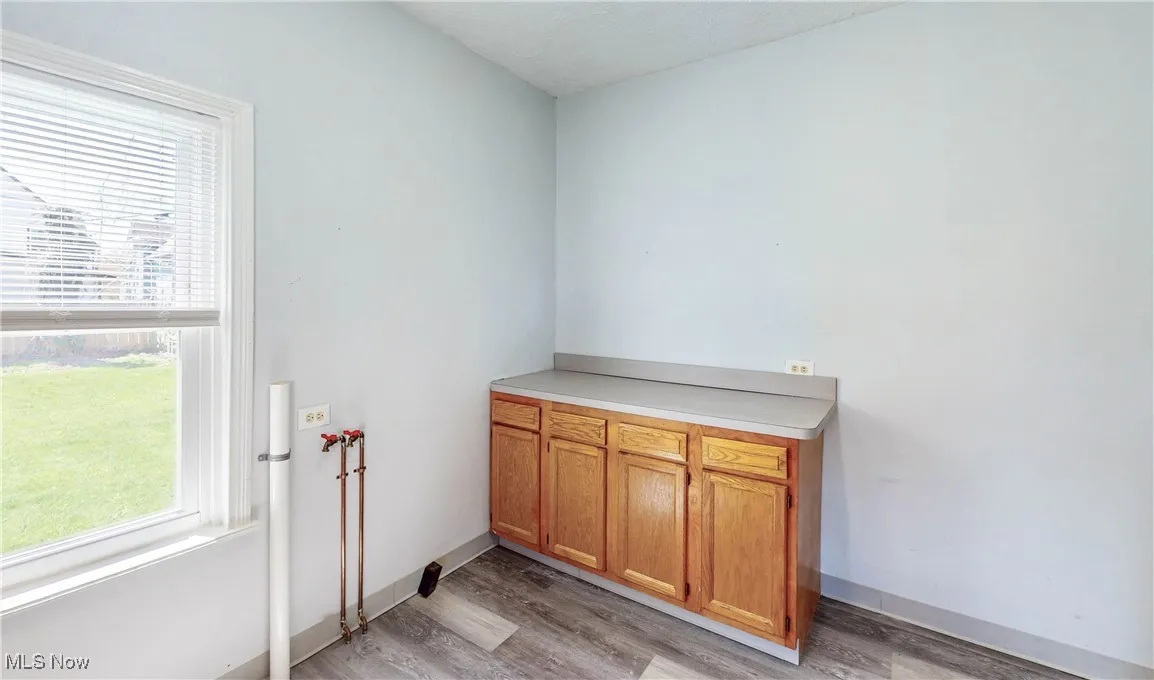 Washroom with light wood finished floors, cabinet space, and hookup for a washing machine