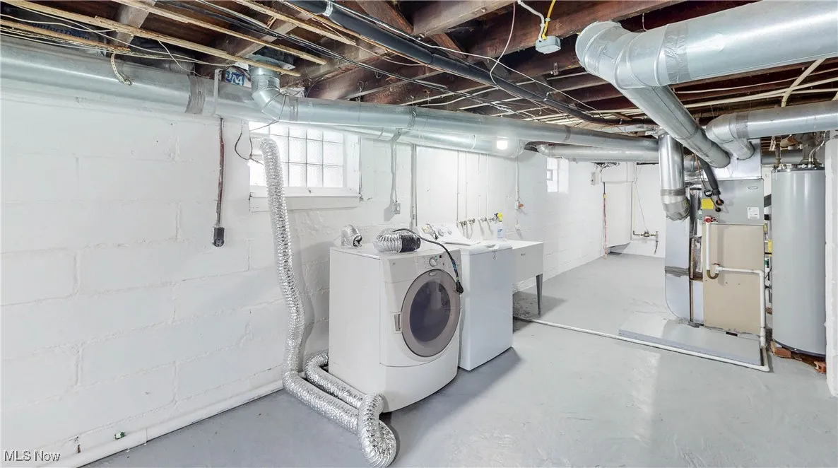 Basement with water heater, heating unit, washing machine and dryer, and plenty of natural light