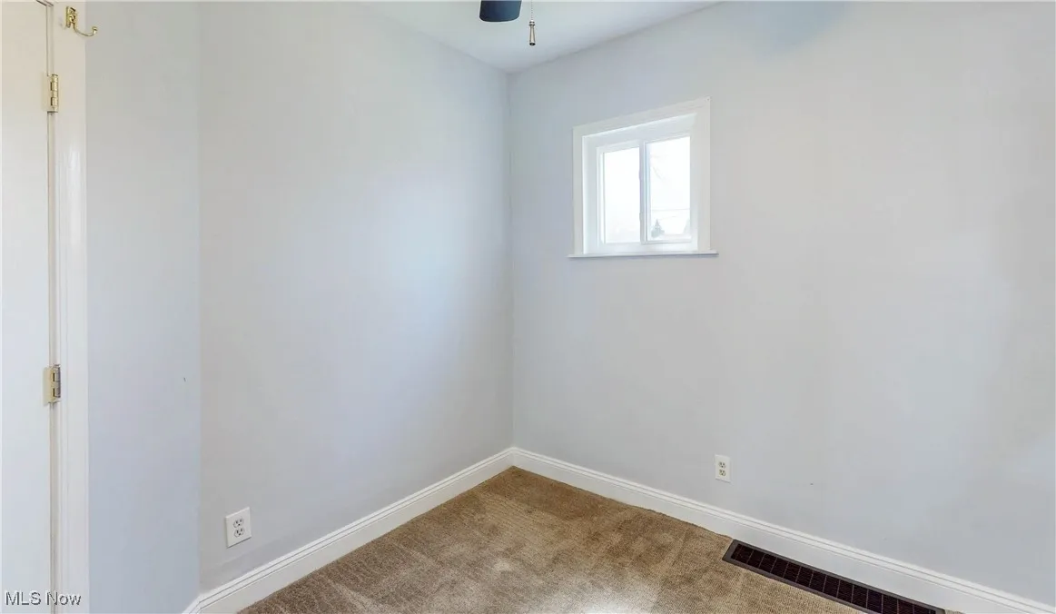 Carpeted spare room featuring baseboards and a ceiling fan