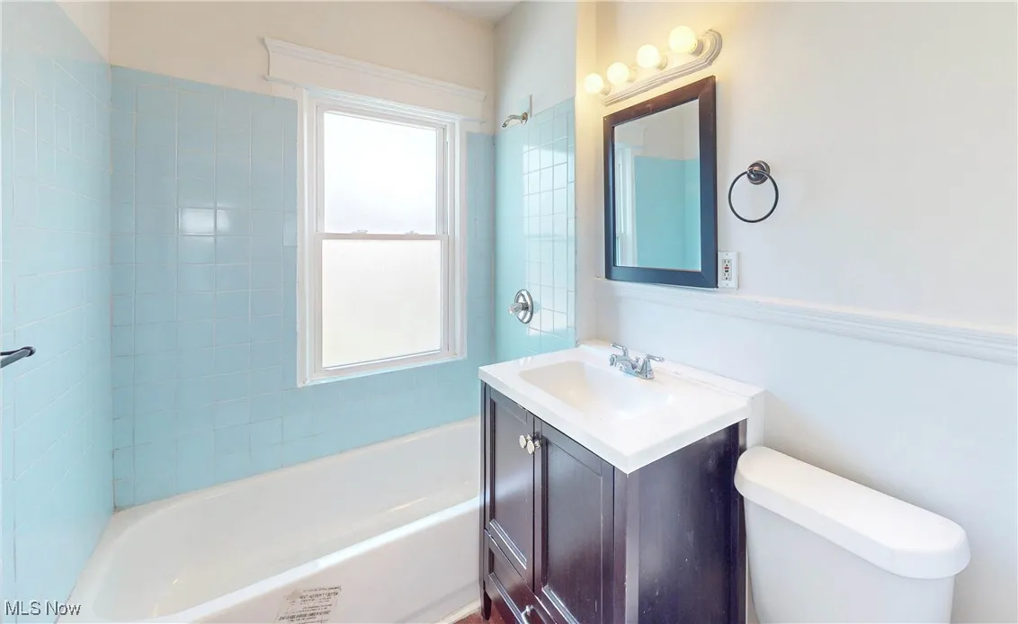 Bathroom featuring vanity, toilet, and shower / washtub combination