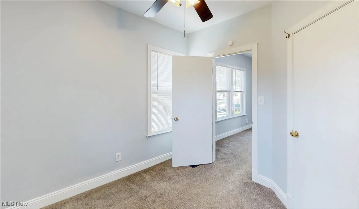 Carpeted spare room featuring ceiling fan and baseboards