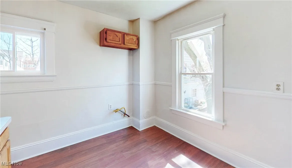 Spare room featuring dark wood-style floors, plenty of natural light, and baseboards