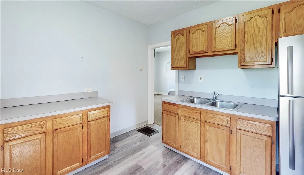 Kitchen with a sink, freestanding refrigerator, light wood finished floors, and light countertops