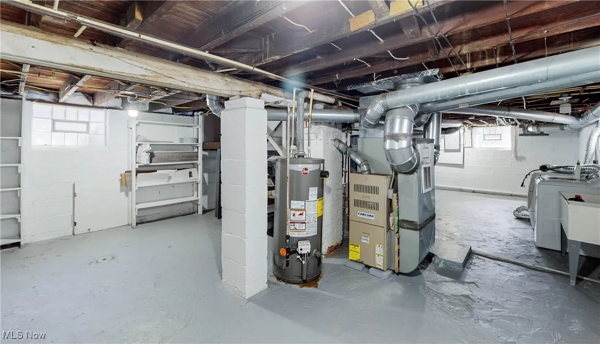 Below grade area featuring water heater, heating unit, and separate washer and dryer