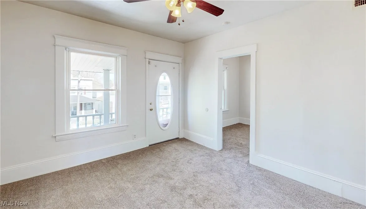 Foyer featuring ceiling fan, carpet floors, and baseboards