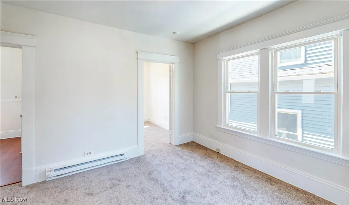 Spare room with baseboard heating, carpet floors, and baseboards