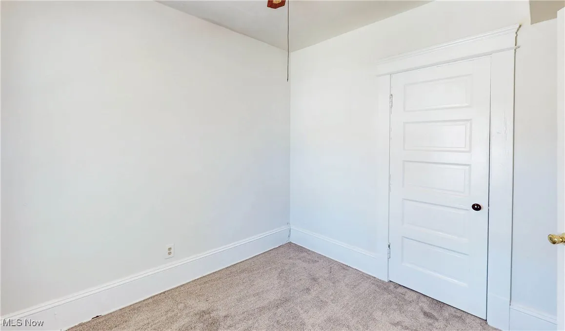 Spare room featuring carpet, baseboards, and ceiling fan