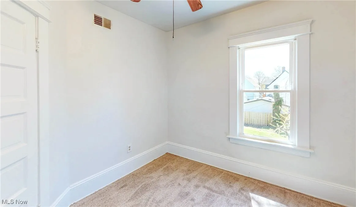 Empty room featuring carpet flooring, baseboards, and a ceiling fan