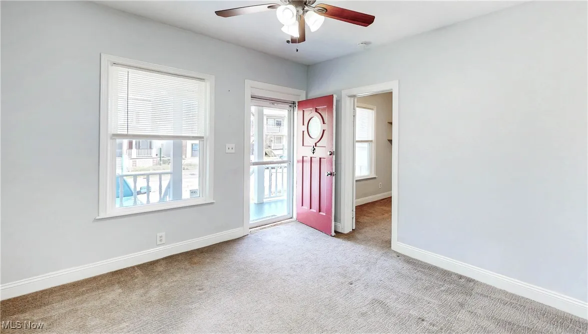 Carpeted foyer featuring ceiling fan and baseboards