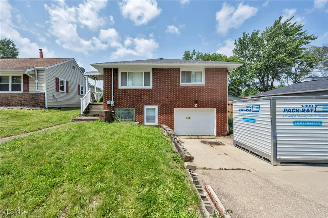 View of front of property with concrete driveway, a garage, brick siding, and a front yard