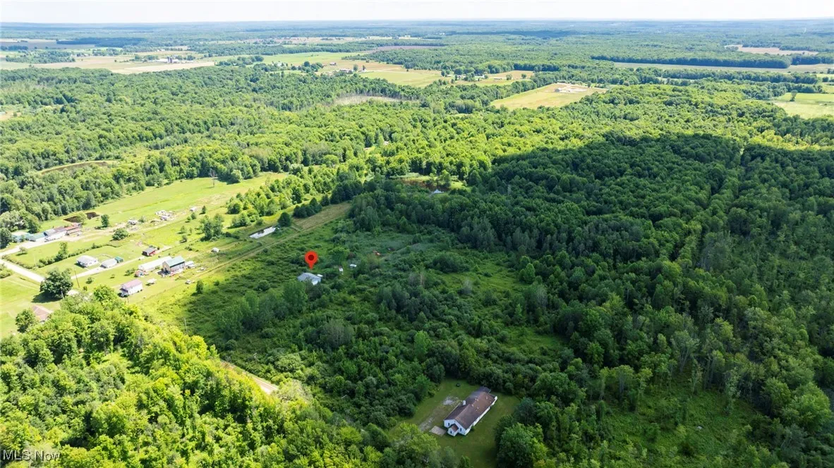 Aerial view of property and surrounding area featuring a forest