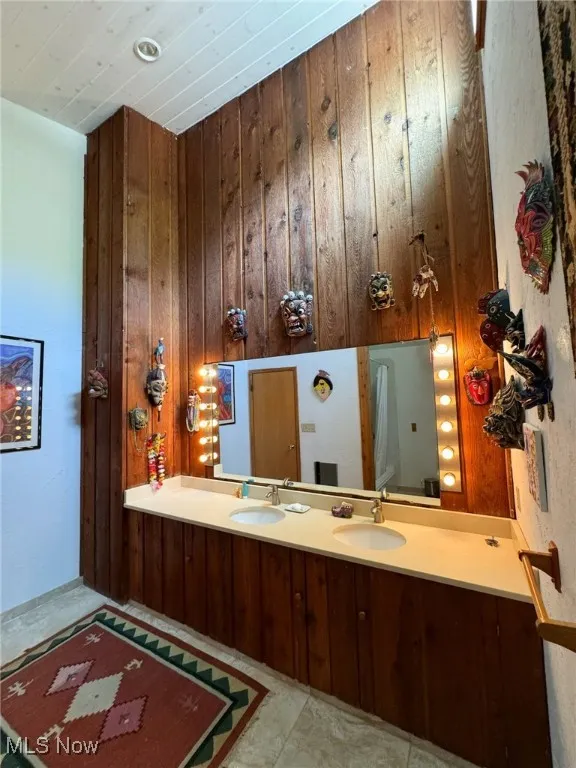 Bathroom with wood walls, double vanity, and wooden ceiling