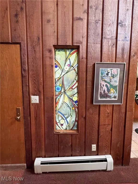 Detailed view of wooden walls, carpet, and a baseboard radiator