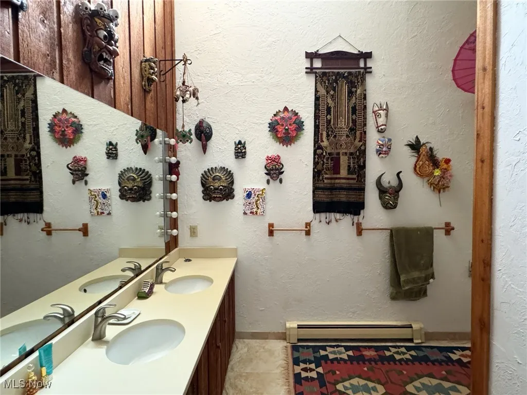 Bathroom featuring a baseboard heating unit, double vanity, and tile patterned floors