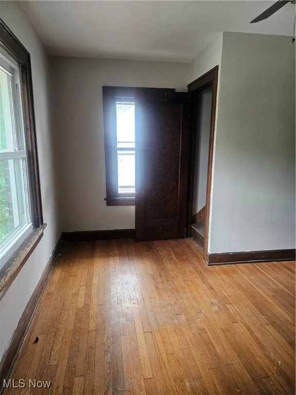 Spare room featuring wood-type flooring, healthy amount of natural light, and a ceiling fan