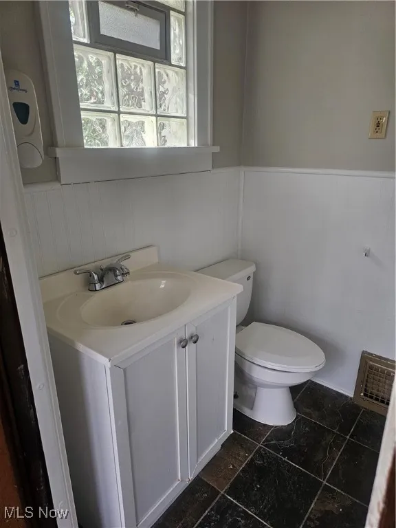 Half bathroom with wainscoting and vanity
