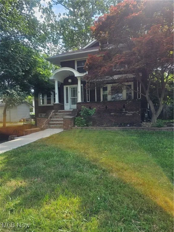 View of front of home with a front lawn, a porch, and brick siding