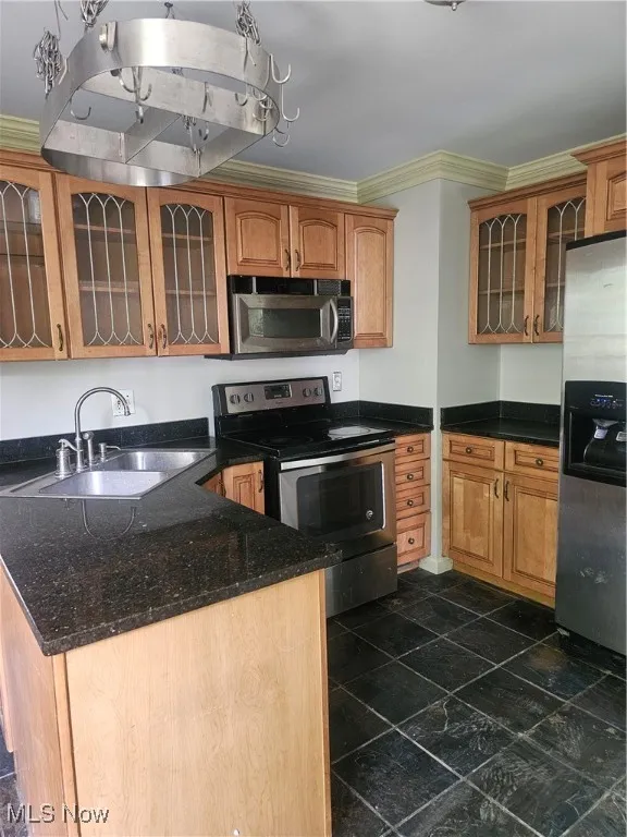 Kitchen with electric range, refrigerator, crown molding, glass insert cabinets, and dark stone counters