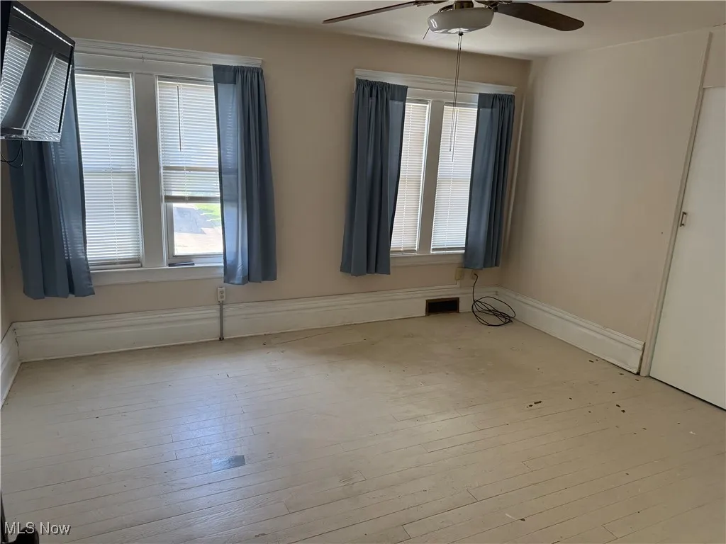 Spare room with a ceiling fan, healthy amount of natural light, and light wood-style floors
