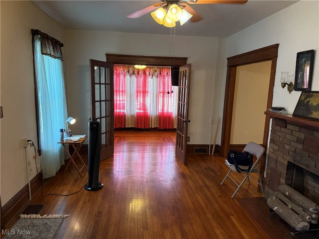 Living room with hardwood / wood-style flooring, a ceiling fan, french doors, and a fireplace
