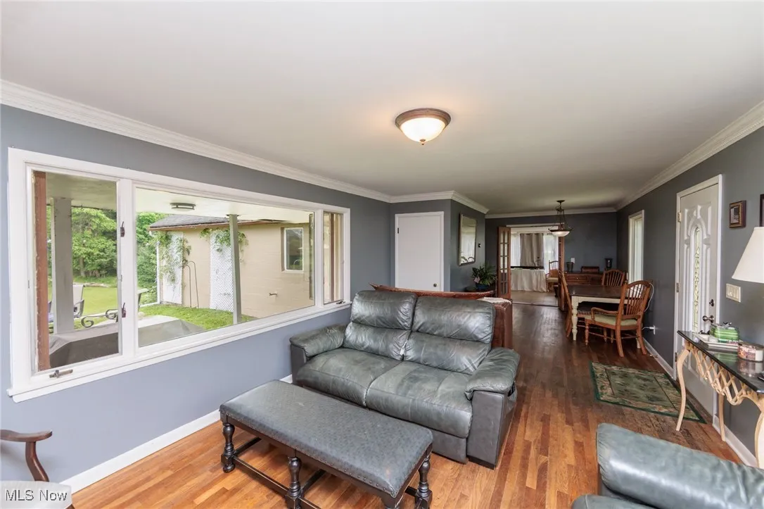 Living area featuring wood finished floors, baseboards, and crown molding