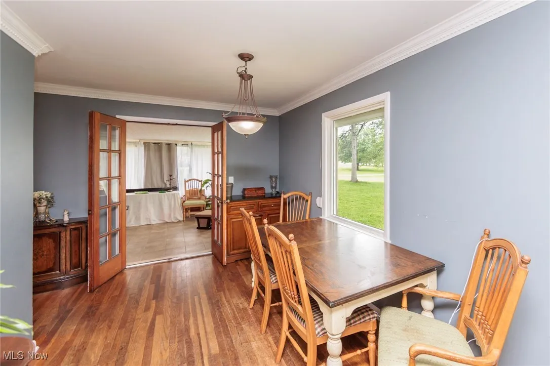 Dining space featuring crown molding, wood finished floors, and french doors