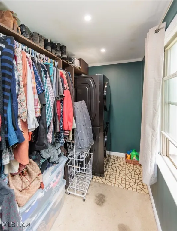 Washroom featuring stacked washer / drying machine, baseboards, and recessed lighting